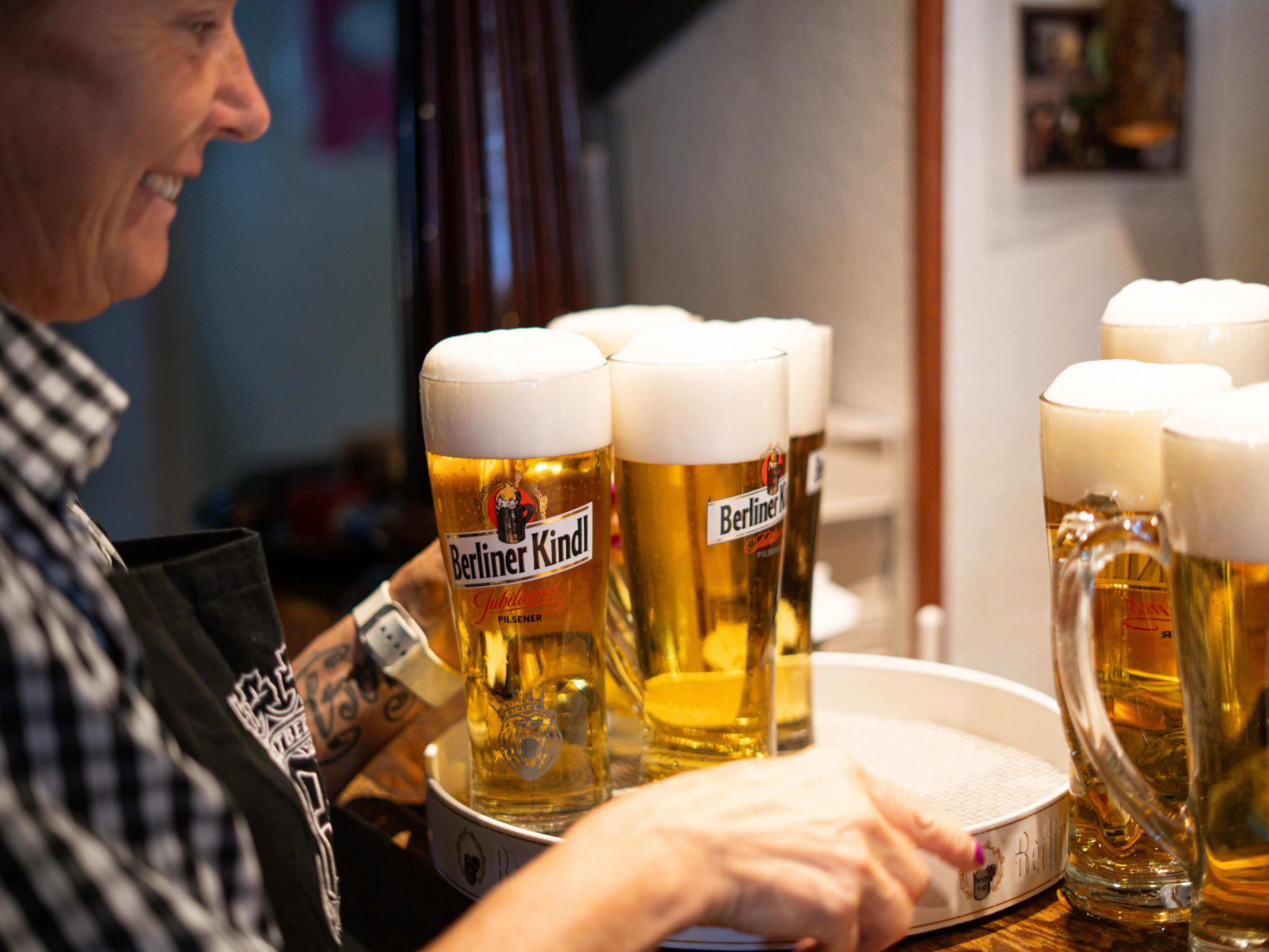 Serviererin trägt ein Tablett mit frisch gezapftem Berliner Kindl Pils